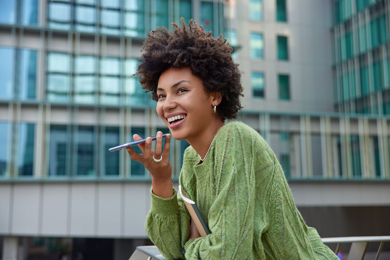 Une jeune femme noire dicte un message vocal à l’assistant depuis son smartphone